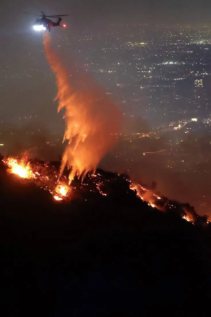 A helicopter spraying fire retardant over the Hollywood Hills